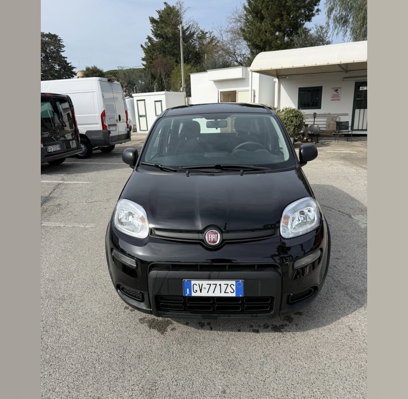 Fiat Panda nera DS Rentcar, vista frontale, targa GV 771ZS, in un piazzale asfaltato con furgoni bianchi e alberi